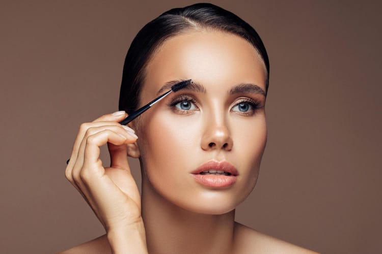 Frau bürstet sich die Augenbrauen